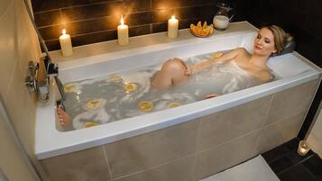 Une baignoire avec des bougies et des tranches d’agrumes.
