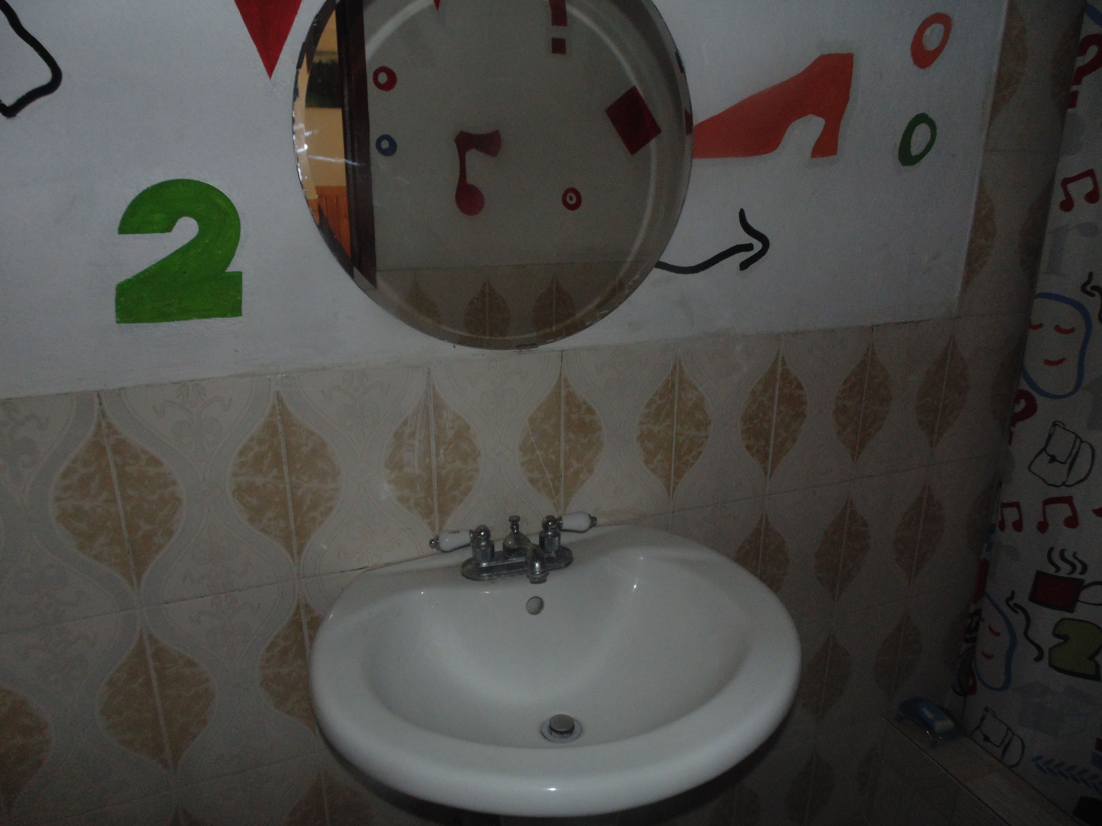 A bathroom with a sink, a mirror, and decorative wall numbers.