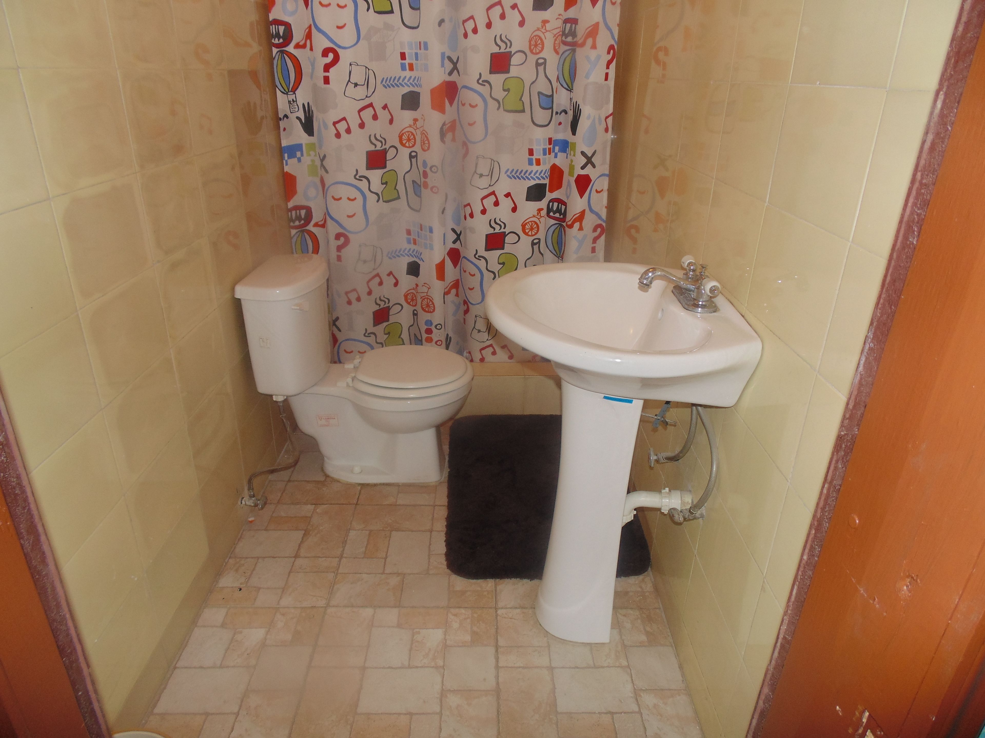 A small bathroom with a toilet, sink, and shower curtain with colorful patterns.