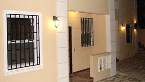 A building with barred windows, a tiled entrance, and a staircase leading to a door. - Metro Residences Hotel (Cap-Haitien)