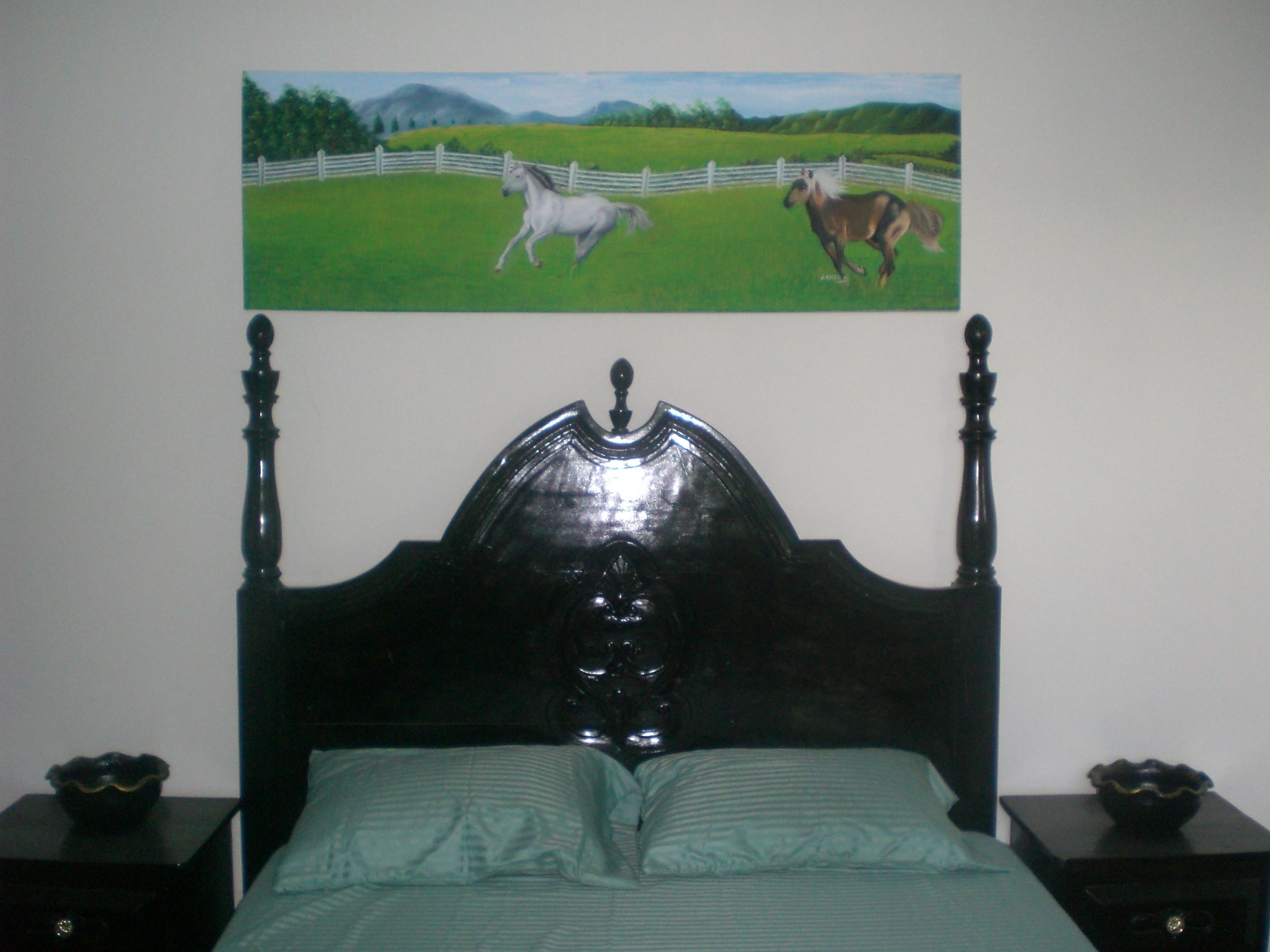 Un dormitorio con cabecera de madera, colcha verde y dos mesitas de noche con cuencos decorativos.