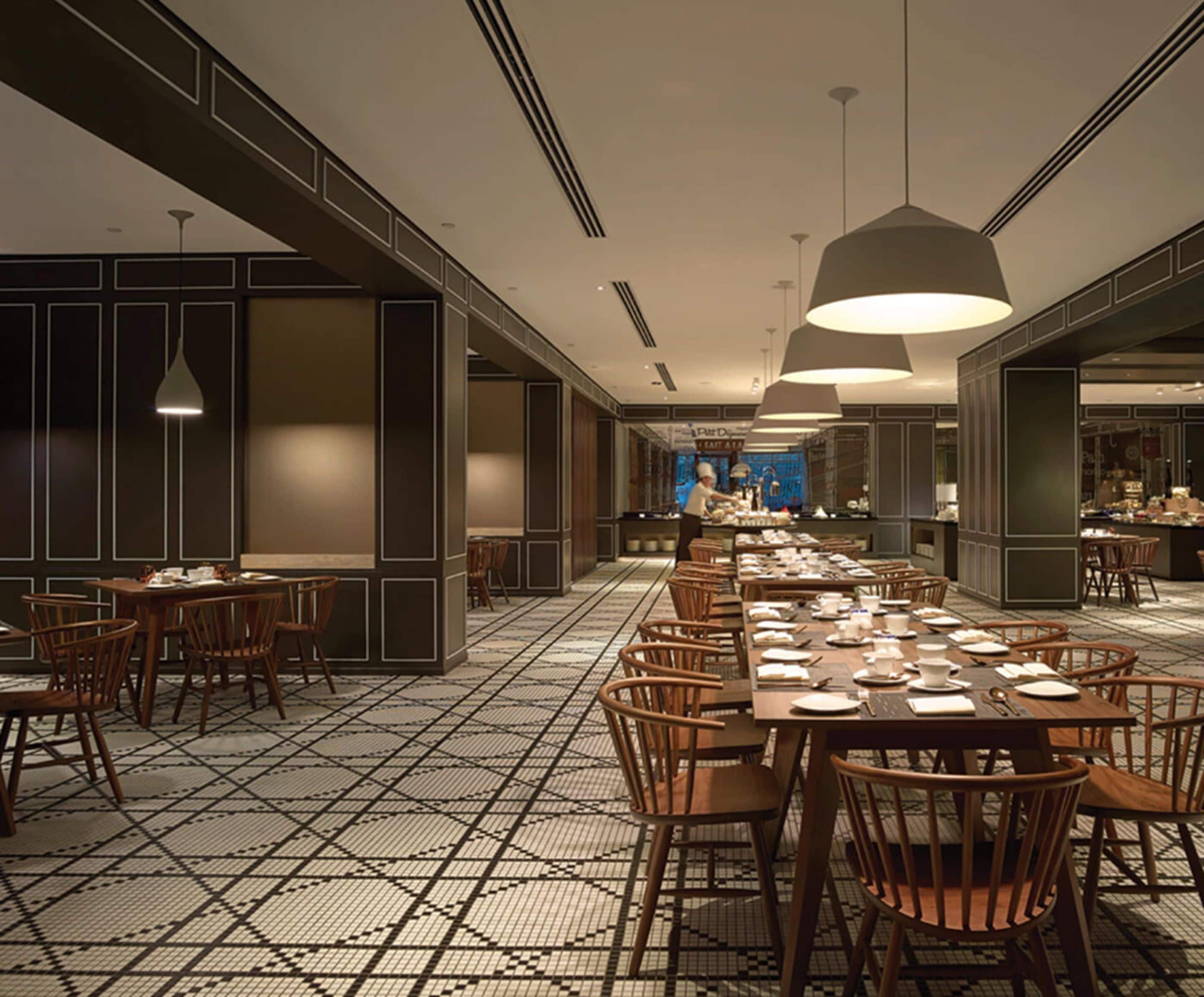A spacious dining area with high ceilings, modern pendant lighting, and a patterned floor.