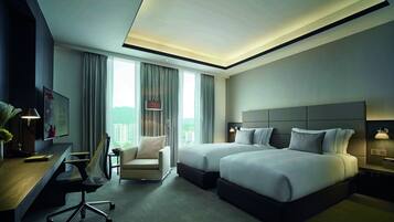 A hotel room with two beds, a desk, a chair, and a large window with curtains.