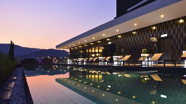 A modern hotel with a pool, lounge chairs, and a view of the mountains. - G Hotel Kelawai (George Town)