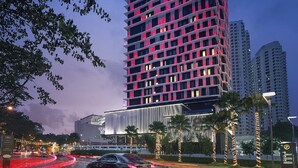A tall, modern hotel with a distinctive red and black facade, multiple balconies, and a parking area with palm trees. - G Hotel Kelawai (George Town)
