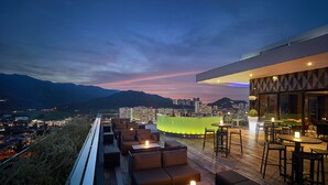 A rooftop bar with seating and a view of a cityscape at dusk. - G Hotel Kelawai (George Town)