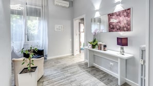 A modern bathroom with a white vanity, a mirror, and a purple lamp. - Gardenia Suite (Rome)