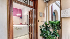A wooden door leading to a reception area with a neon sign and a signboard. - Gardenia Suite (Rome)