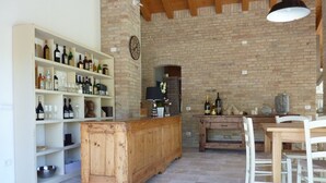 Una cocina rústica con armarios de madera, pared de ladrillo y zona de comedor con sillas blancas.