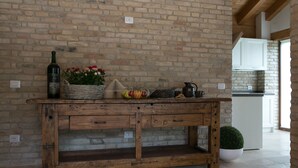 Una cocina rústica con una mesa de madera, un muro de ladrillo y una planta en maceta.