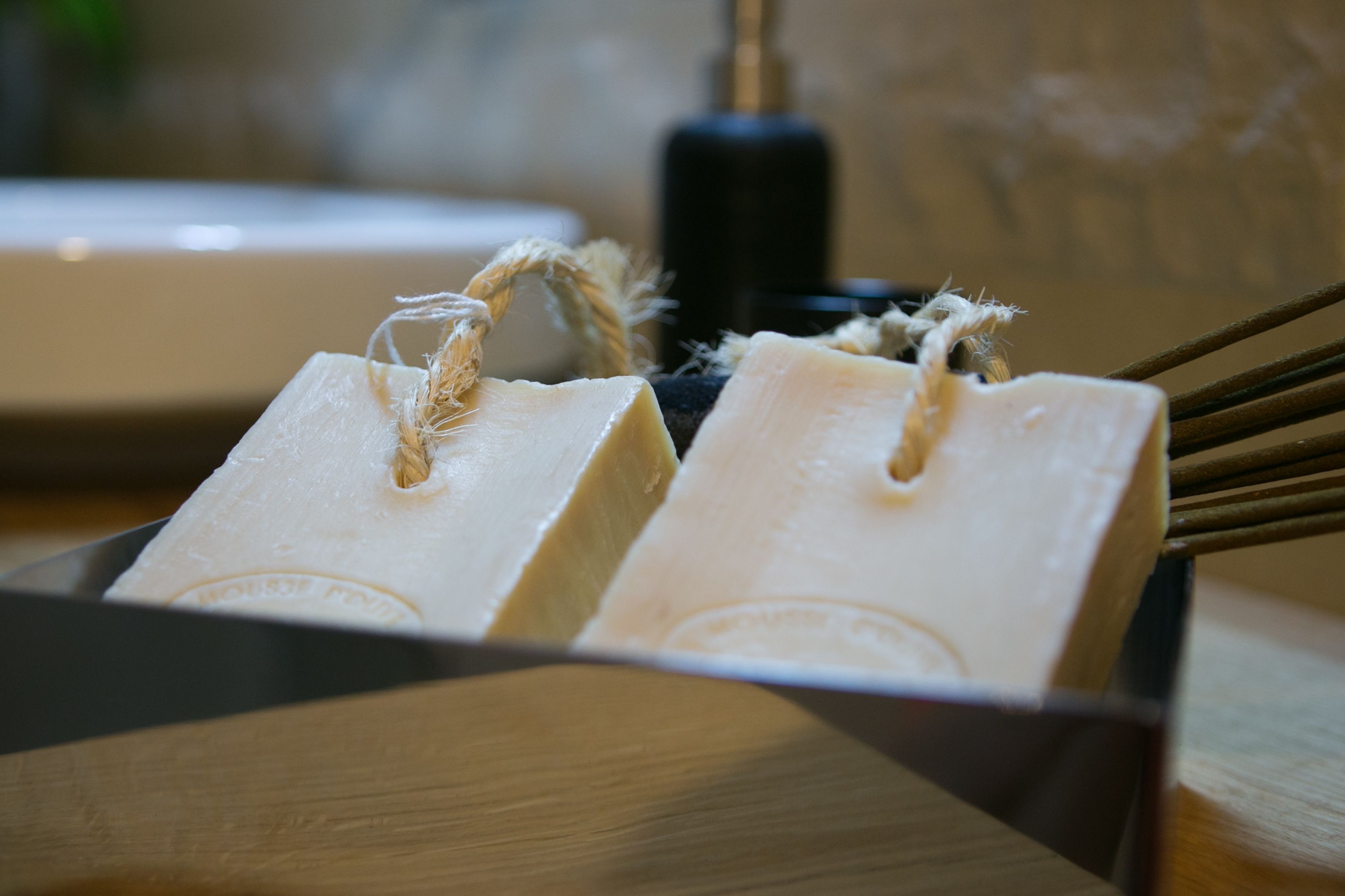 A wooden box containing two bars of soap with a rope handle, placed on a wooden surface.