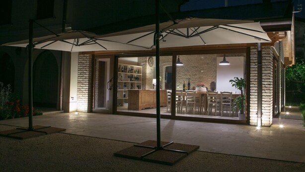 Un patio al aire libre con una zona de estar techada, una mesa de madera y un muro de piedra.