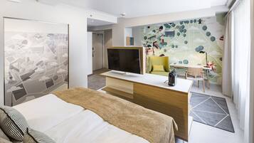 Ein Hotelzimmer mit Bett, Schreibtisch, Stuhl, Fernseher und einer Wand mit Stadtbild-Mural.