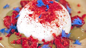 Un postre con base blanca, cobertura roja y flores comestibles azules.