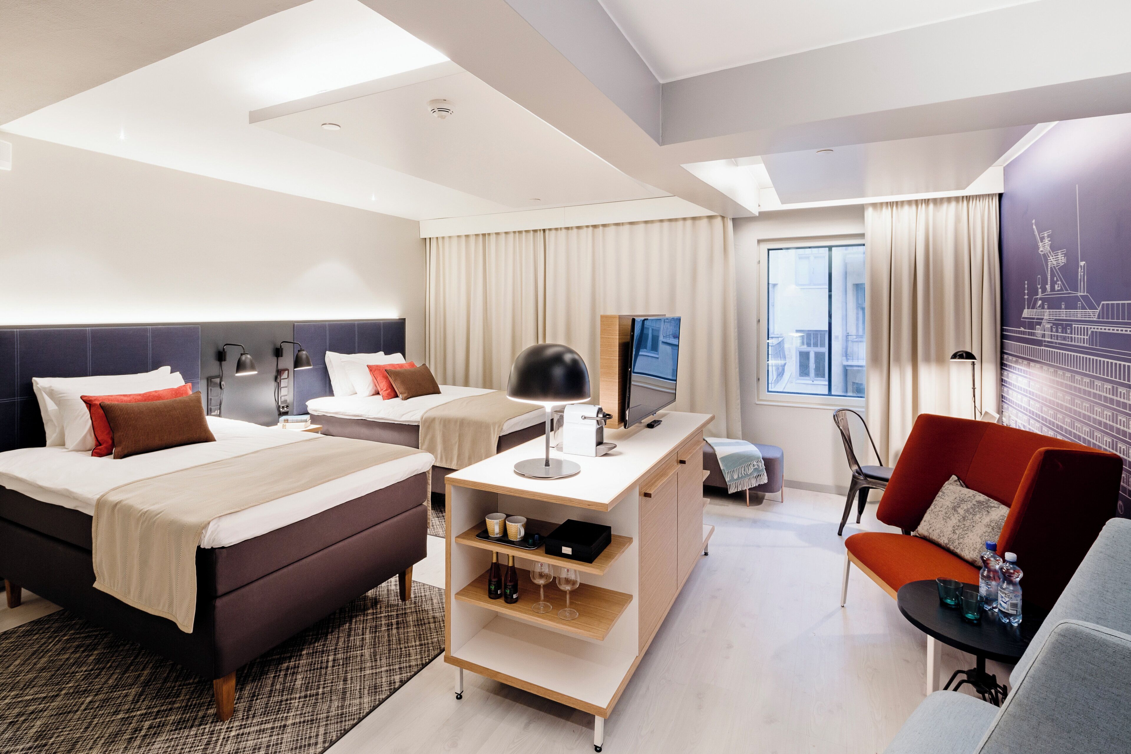 Una habitación de hotel moderna con cama, escritorio, zona de estar y un amplio ventanal.