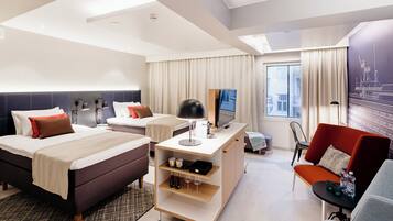 Una habitación de hotel moderna con cama, escritorio, zona de estar y un amplio ventanal.