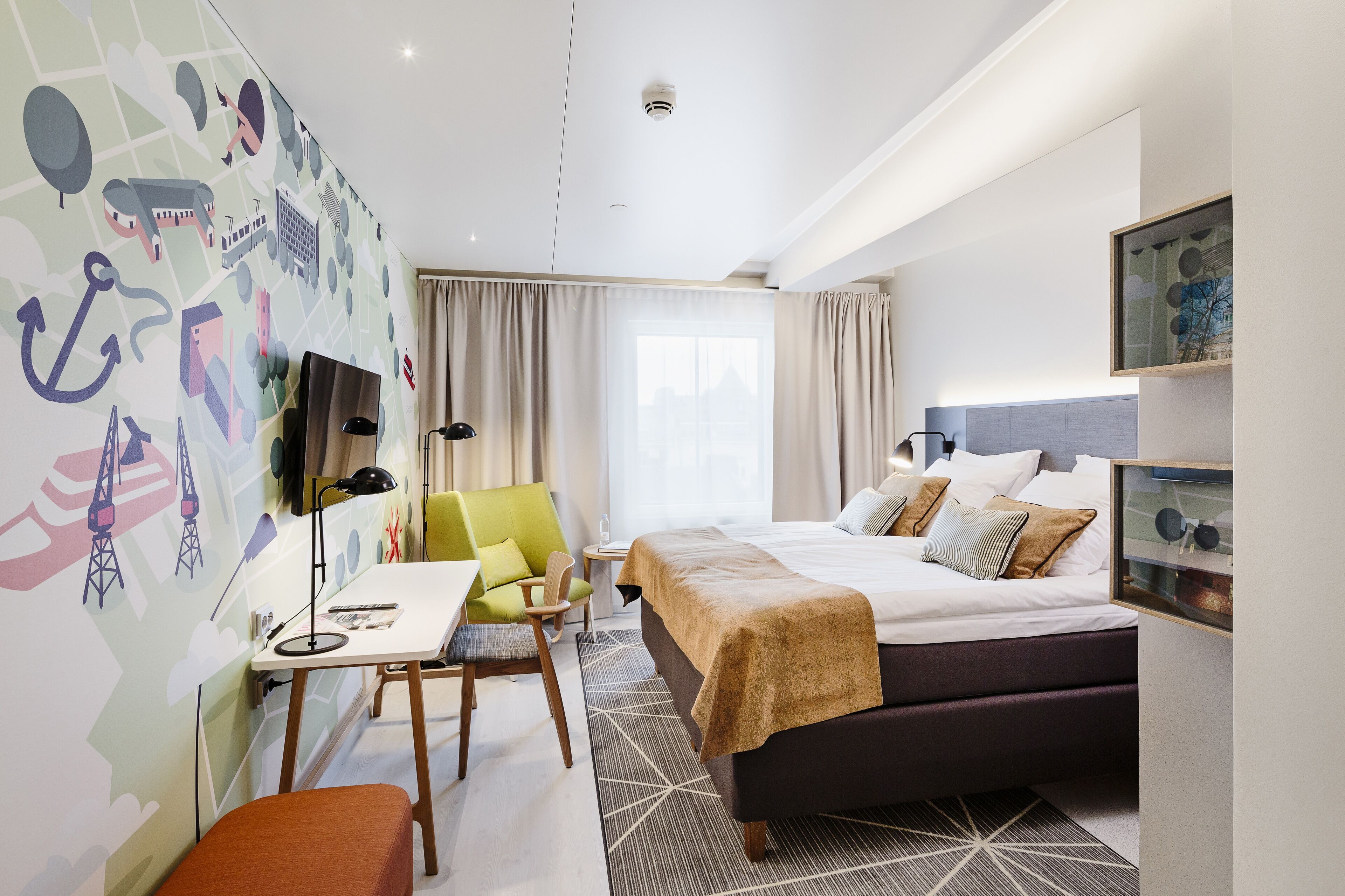 Una habitación de hotel con cama, escritorio, silla, televisor y ventana con cortinas.