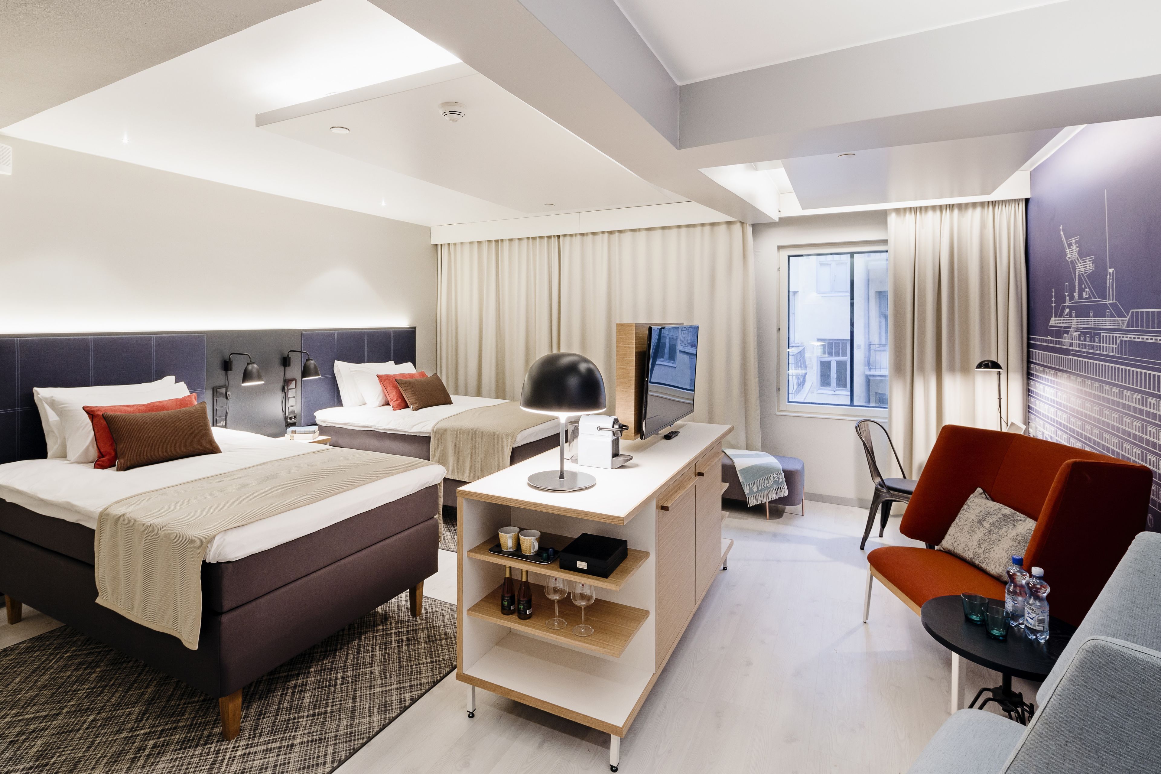 Een moderne hotelkamer met een bed, een bureau, een bank en een televisie.