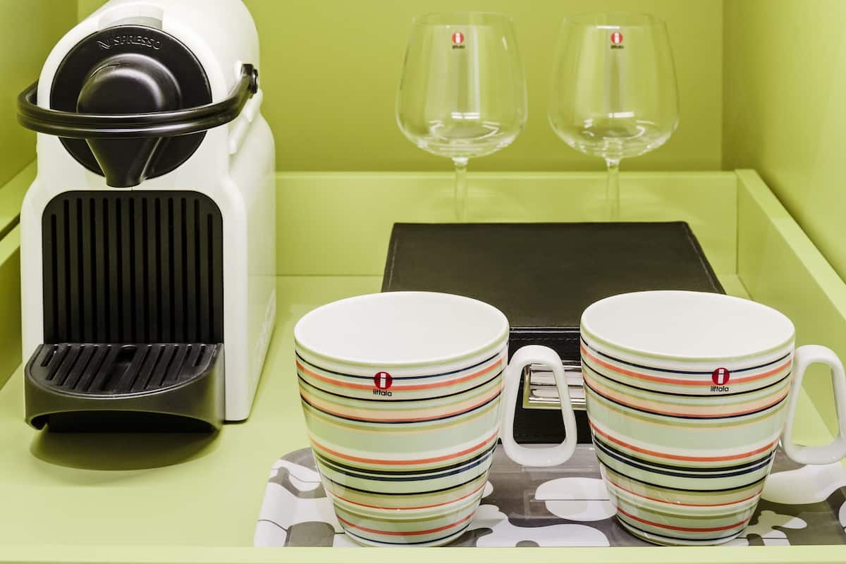 A Nespresso coffee machine, two glasses, and a tray with two striped cups.