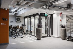 A hotel entrance with a bike parking area, a turnstile, and a sign for hotel lifts. - Hotel Indigo Helsinki - Boulevard by IHG (Helsinki)