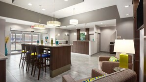 A modern hotel lobby with a bar area, seating, and a reception desk.