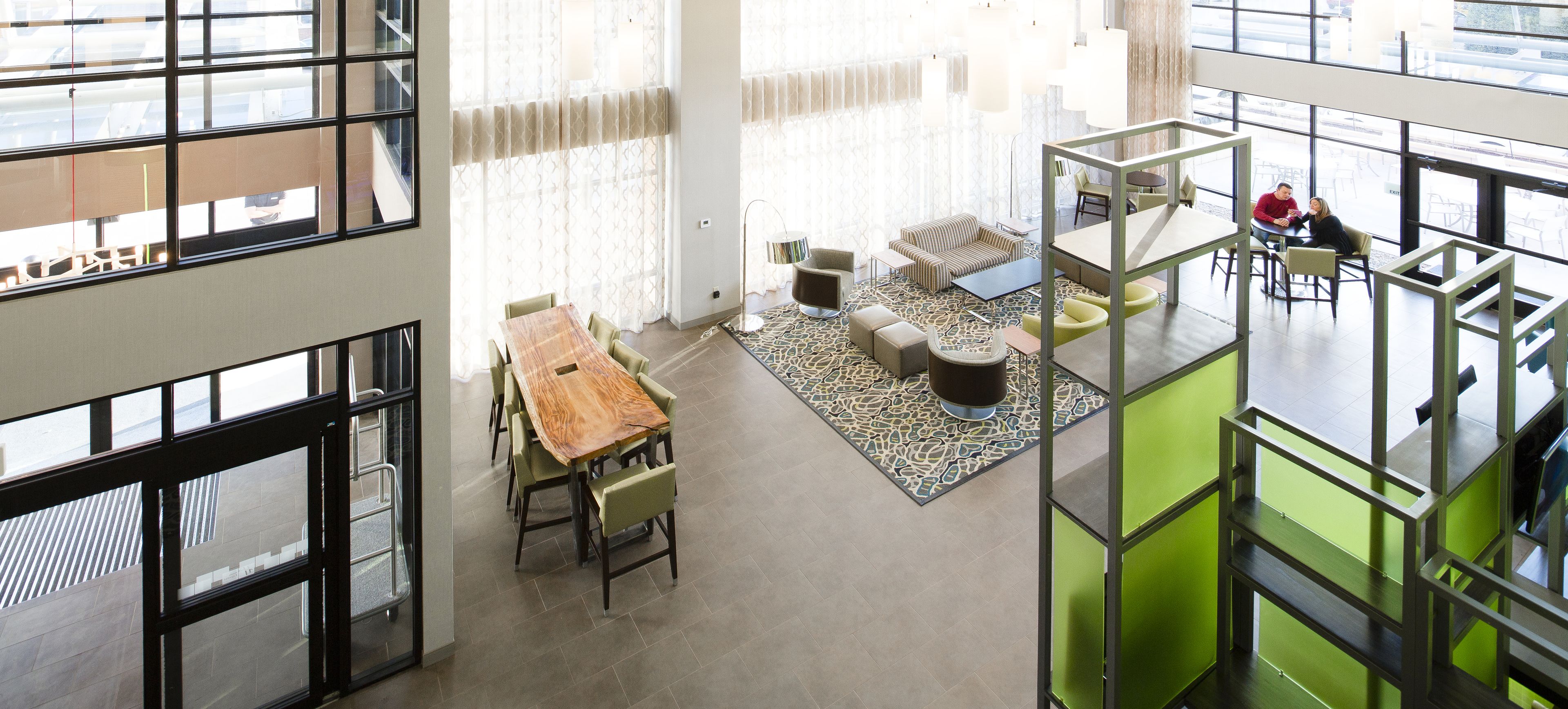 Un espacio amplio, de varios niveles y distribución abierta, con una mesa de comedor, sofás y una pared de acento verde.