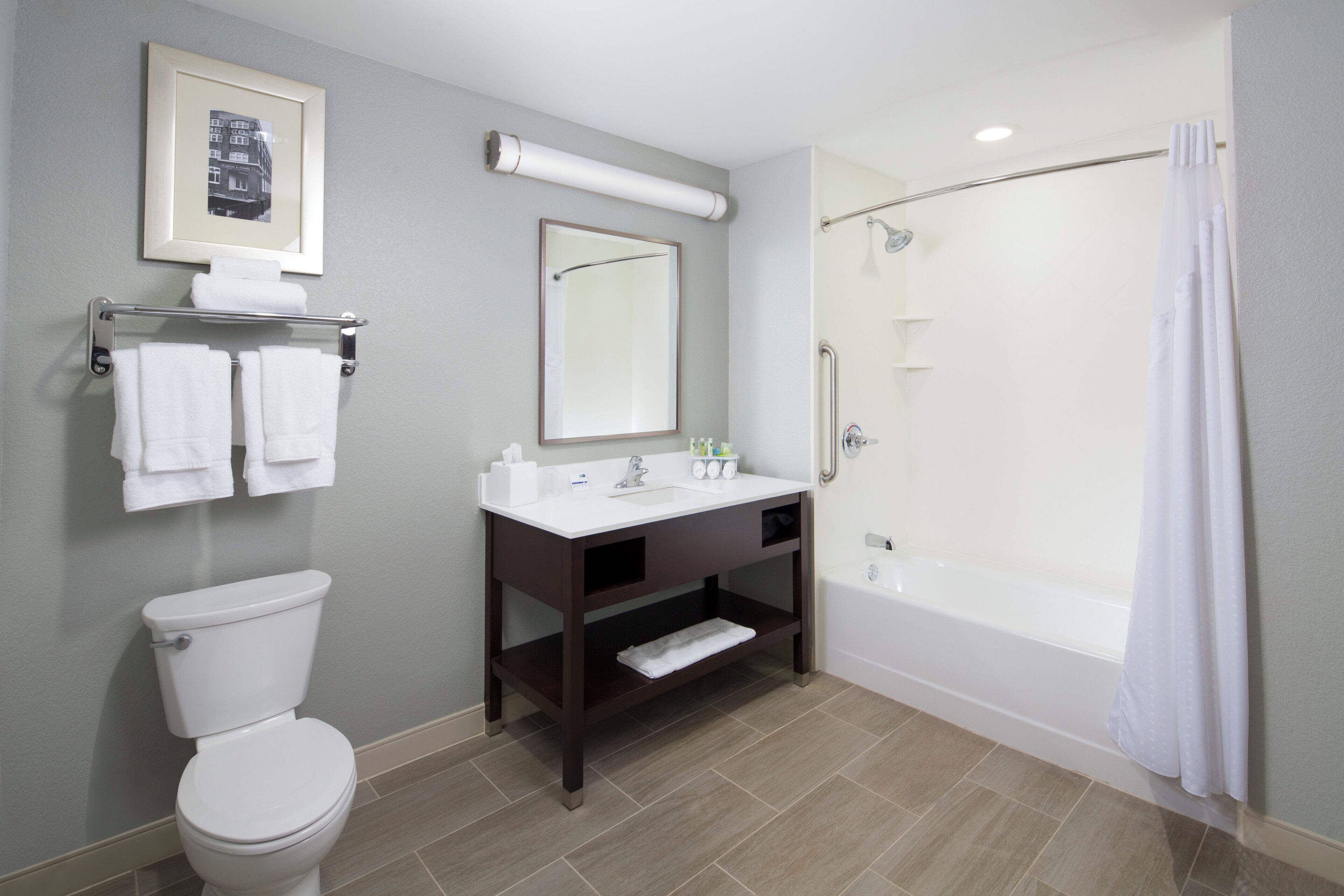 A bathroom with a toilet, sink, mirror, and shower.