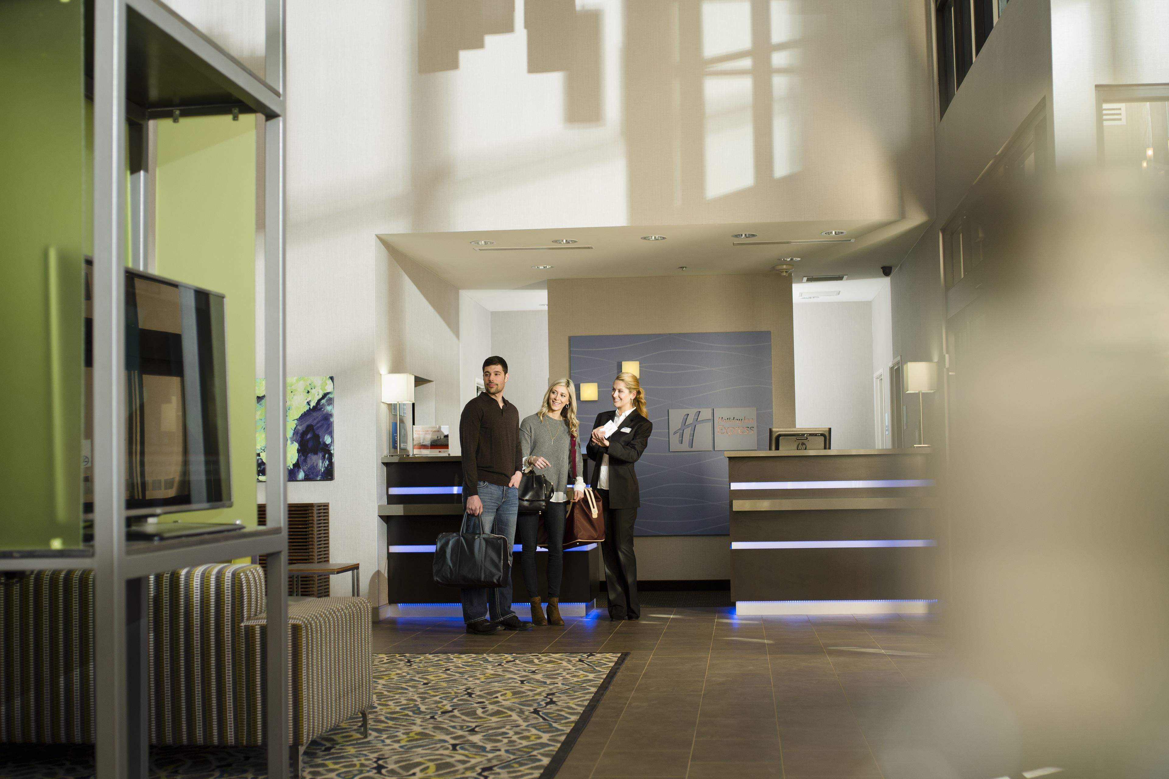 A hotel reception area with a modern design, including a reception desk, seating area, and a large window allowing natural light.