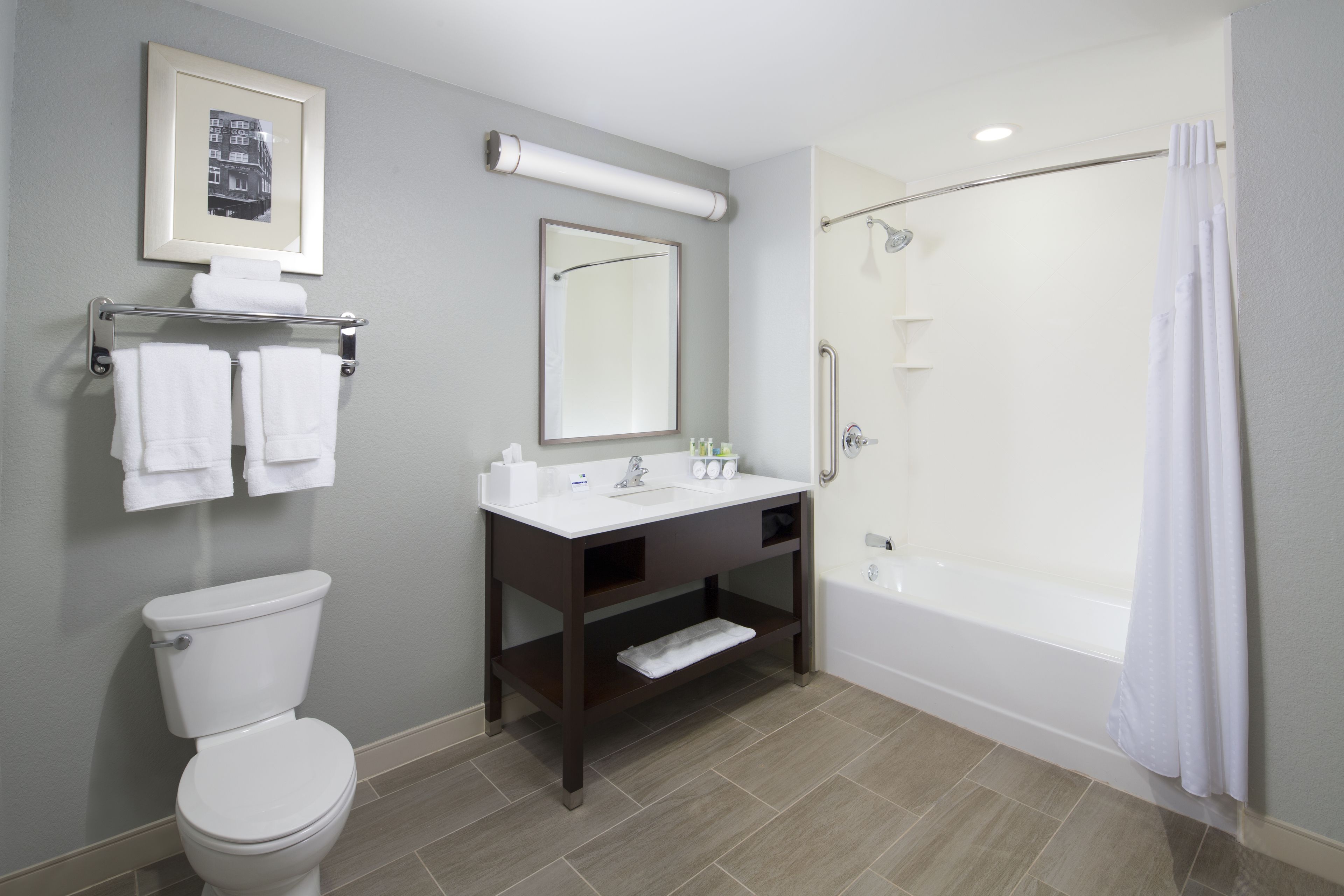A modern bathroom with a toilet, sink, mirror, and shower.