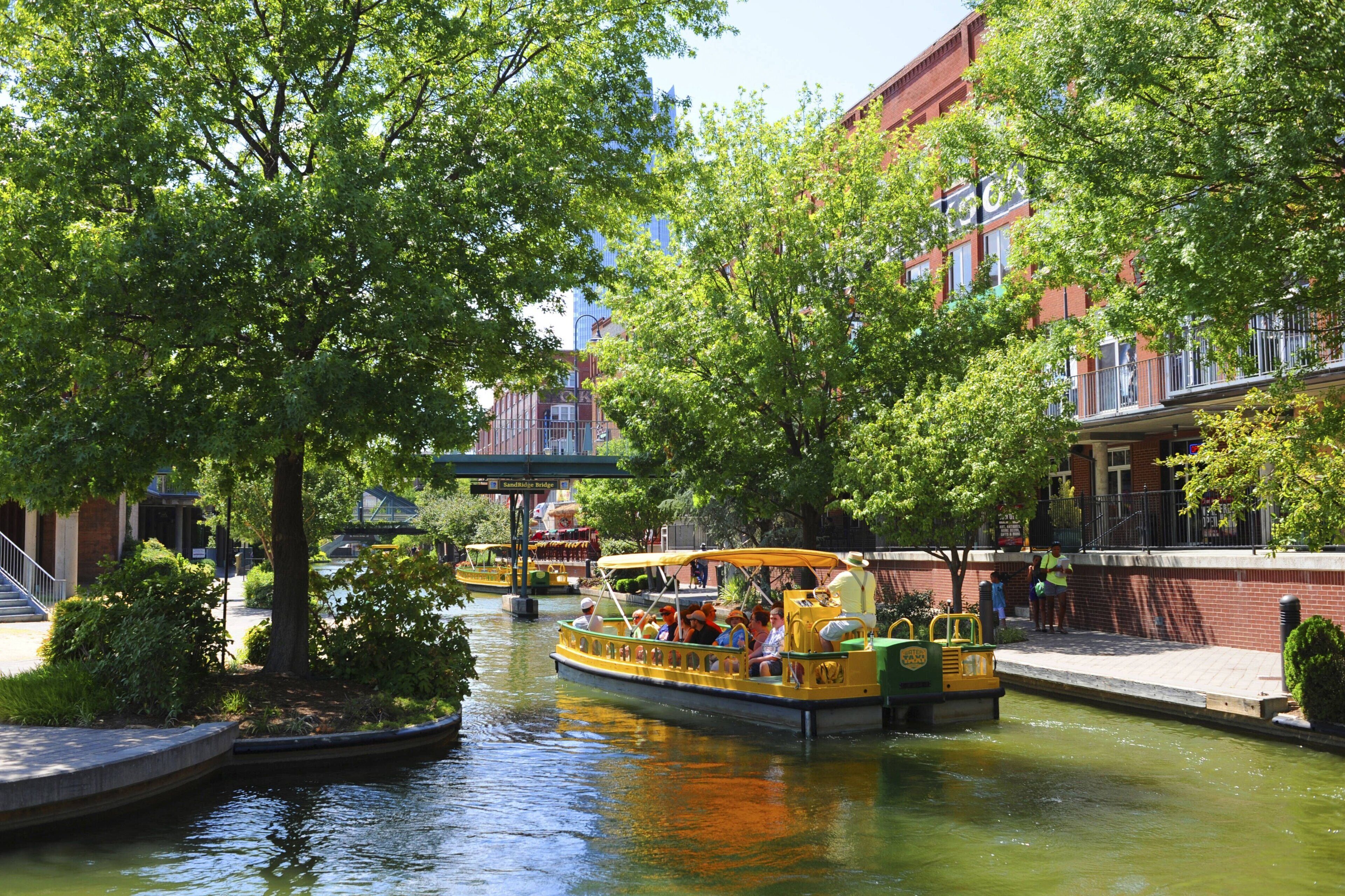 Un canal bordé de bateaux, d’arbres et de bâtiments.