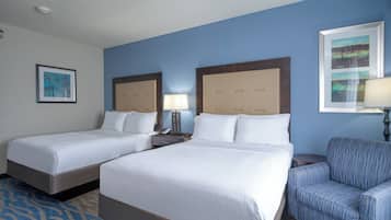 Ein Hotelzimmer mit zwei Betten, einer blauen Wand und einem gerahmten Bild.