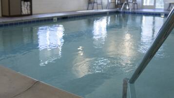 An indoor swimming pool with clear water, tiled walls, and a lifeguard sign.
