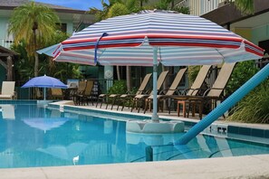 Uma área de piscina com espreguiçadeiras e guarda-sóis.