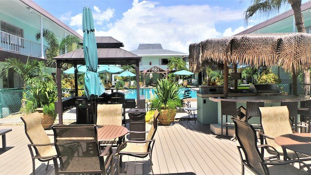 Una terraza con mobiliario exterior, piscina y un bar tiki.