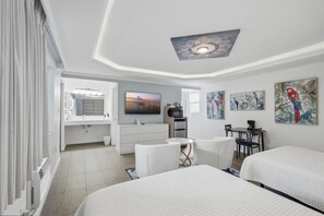 Ein Hotelzimmer mit zwei Betten, einem Schreibtisch, einem Sessel, einem Fernseher und Bildern an den Wänden.
