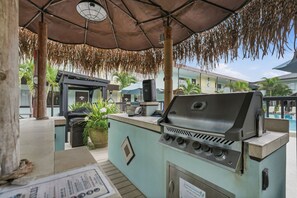 Un área de parrilla al aire libre con estufa a gas, un reloj y un letrero que indica el uso de propano.
