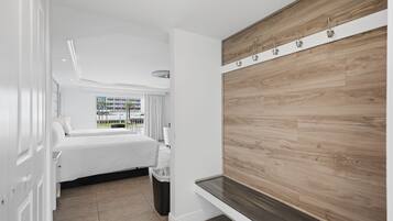 Quarto de hotel com uma cama, um painel de parede em madeira, uma janela com vista e uma lixeira.