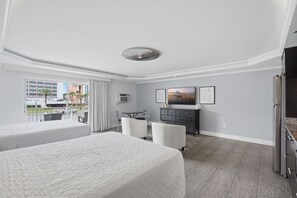 Une chambre d’hôtel avec deux lits, un bureau, une télévision et une vue sur la ville.