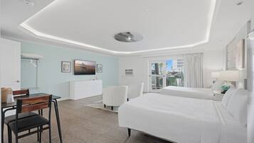 A hotel room with a bed, a desk, a chair, a wardrobe, and a view of the outside.