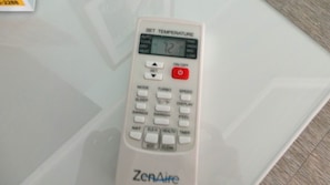 Un control remoto blanco con varios botones y una pantalla digital.