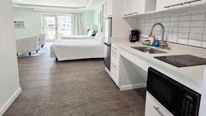 Una habitación de hotel moderna con kitchenette, una cama y vistas al exterior.
