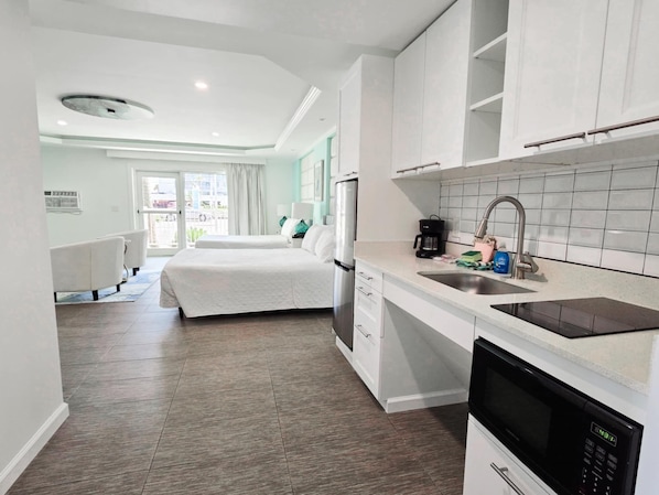 Una habitación de hotel moderna con kitchenette, una cama y vistas al exterior.