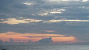 Un atardecer sobre una masa de agua con nubes en el cielo.
