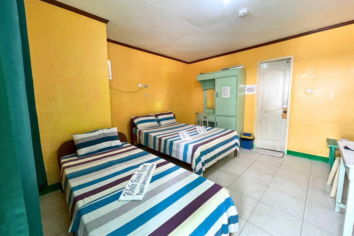 A room with two beds, a green cabinet, and a door with a sign.