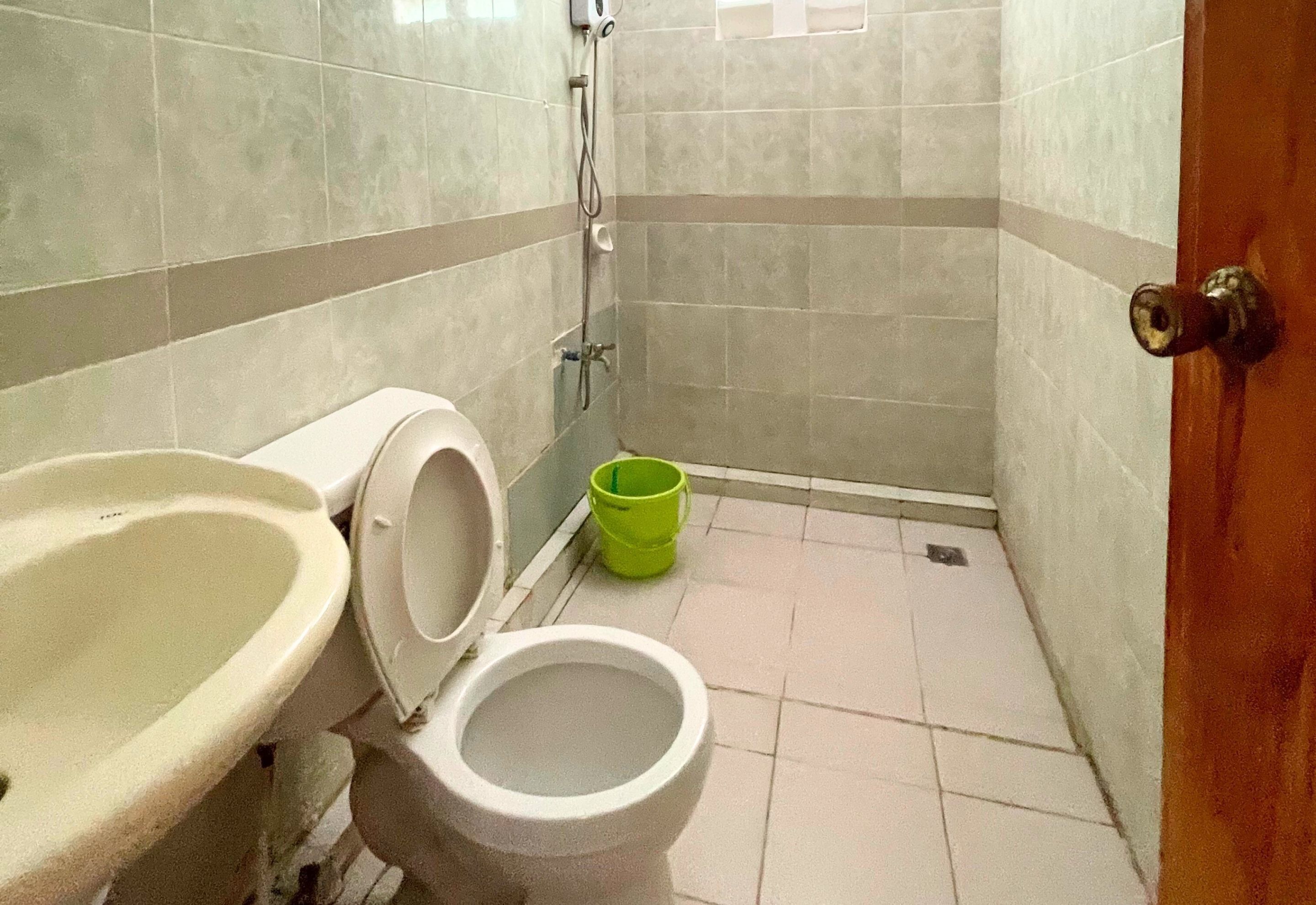A small bathroom with a toilet, sink, and shower.