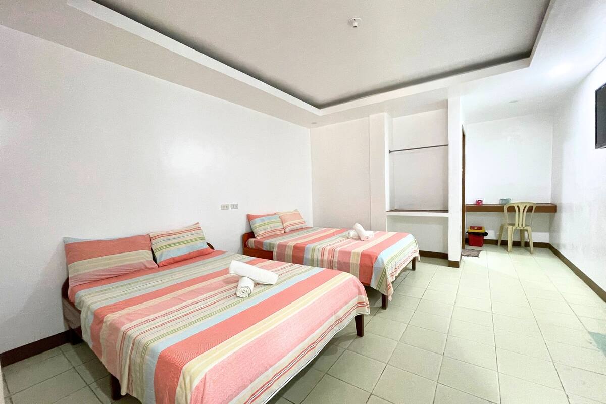 A hotel room with two beds, a desk, and a chair.