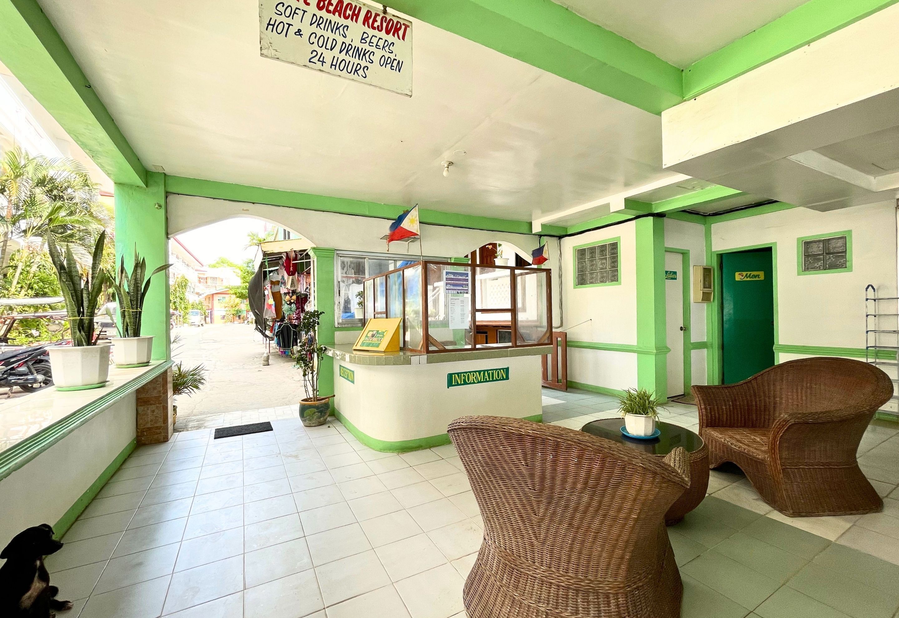 A reception area with a green and white color scheme, a reception desk, wicker chairs, and potted plants.