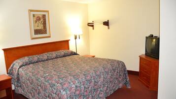 Habitación de hotel con cama, mesita de noche, lámpara, cómoda y televisor.