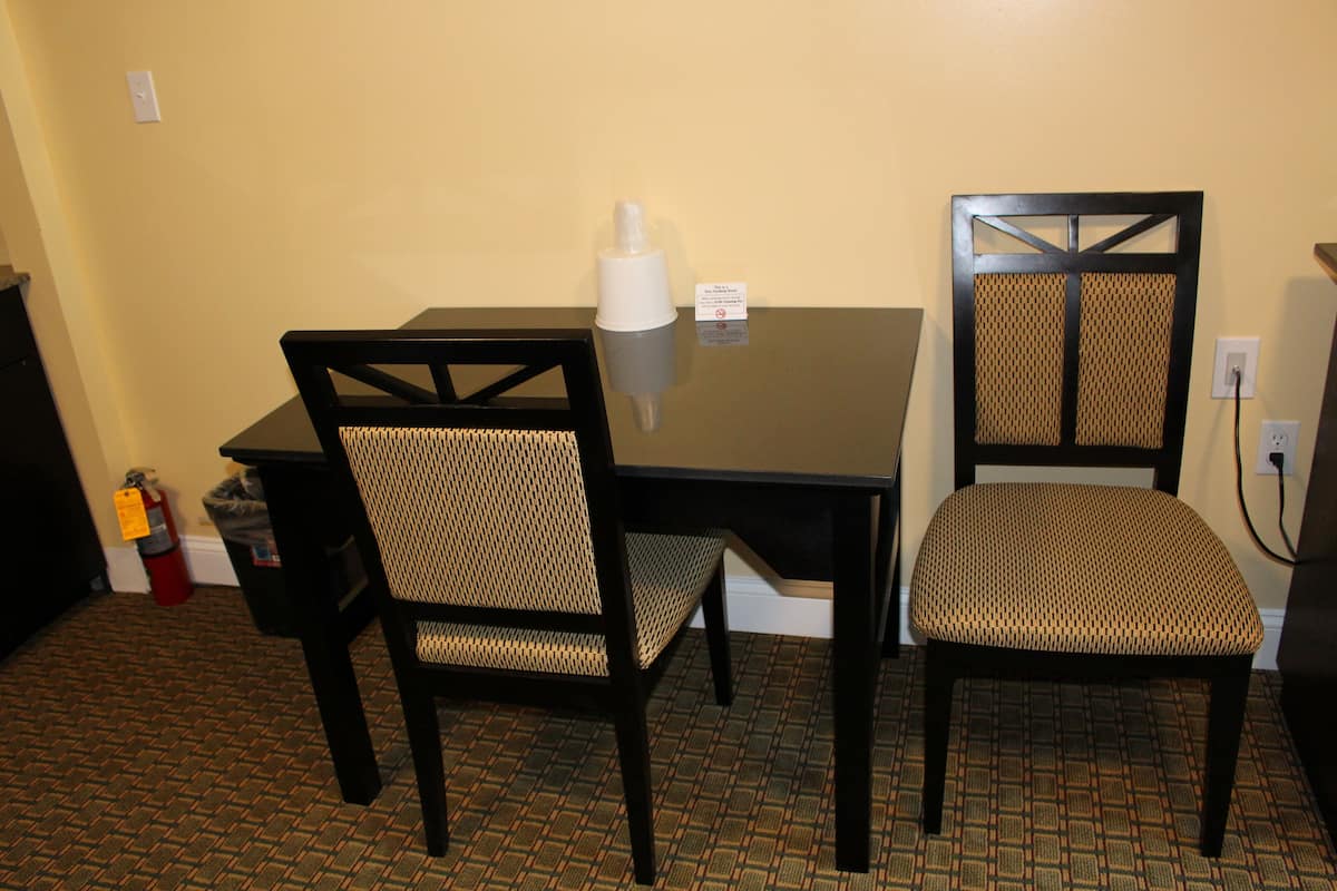 A small dining area with a table and two chairs, a fire extinguisher, and a trash can.