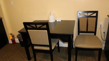 Un pequeño comedor con una mesa y dos sillas, un extintor y un cubo de basura.